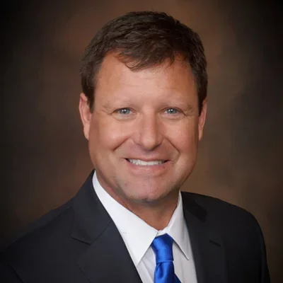 Dr. Louis Kerr smiling while wearing a black suite and blue tie.
